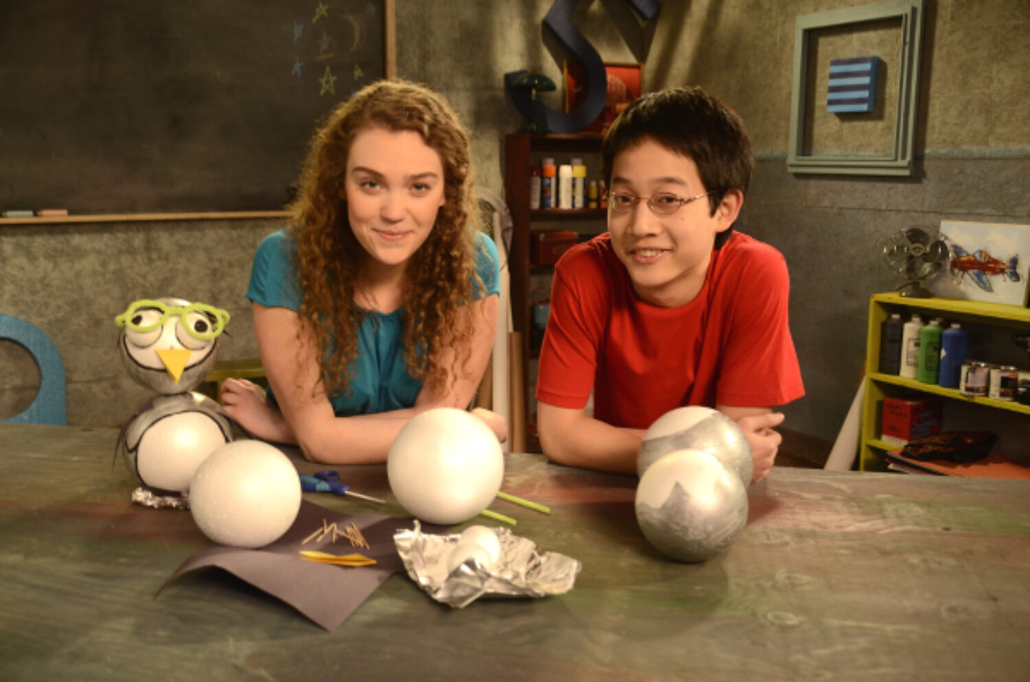 Two children on the cast of The Prime Radicals creating styrofoam ball crafts.