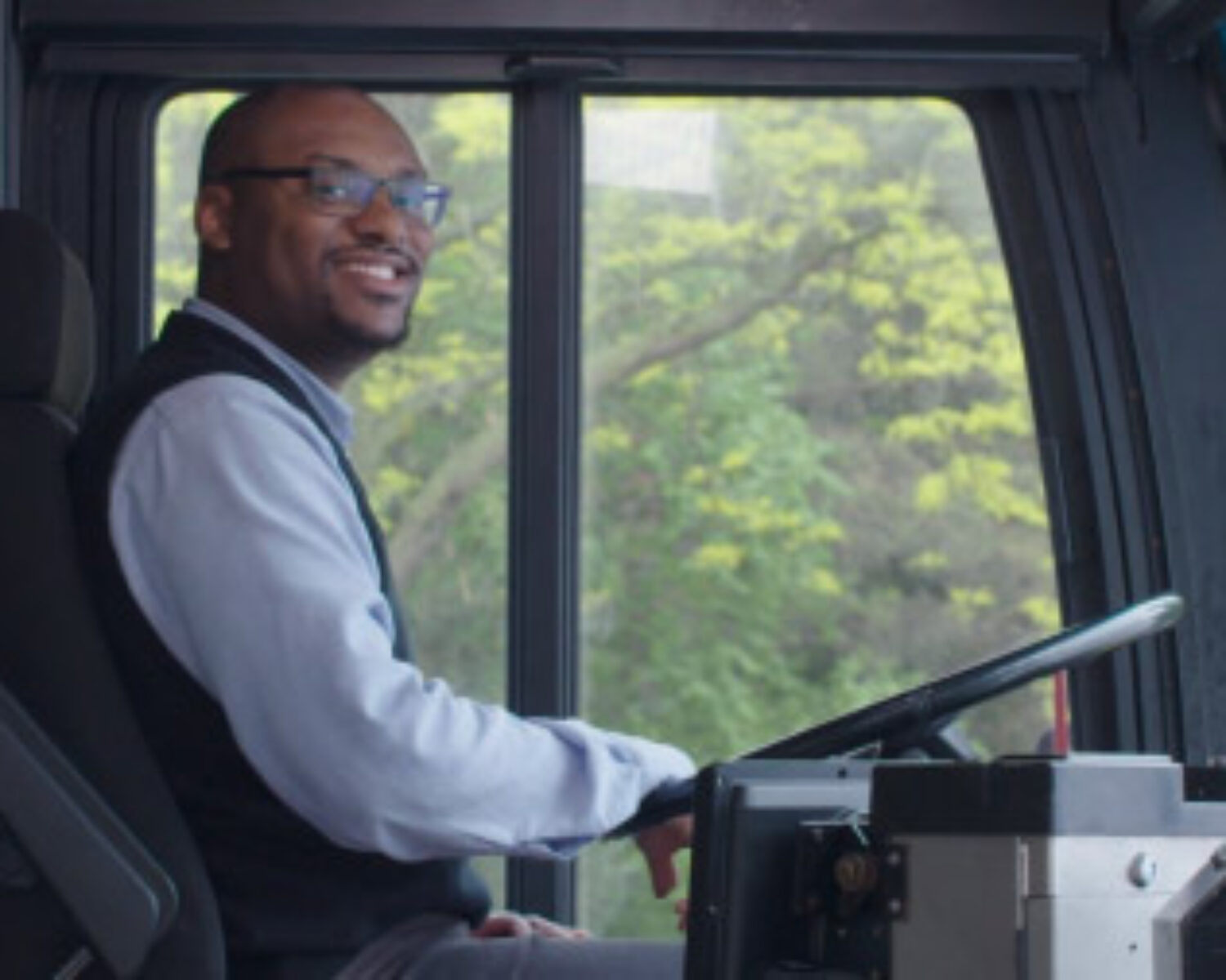 Man sitting in the driver seat of a bus on the set of "B" is for Bus Driver