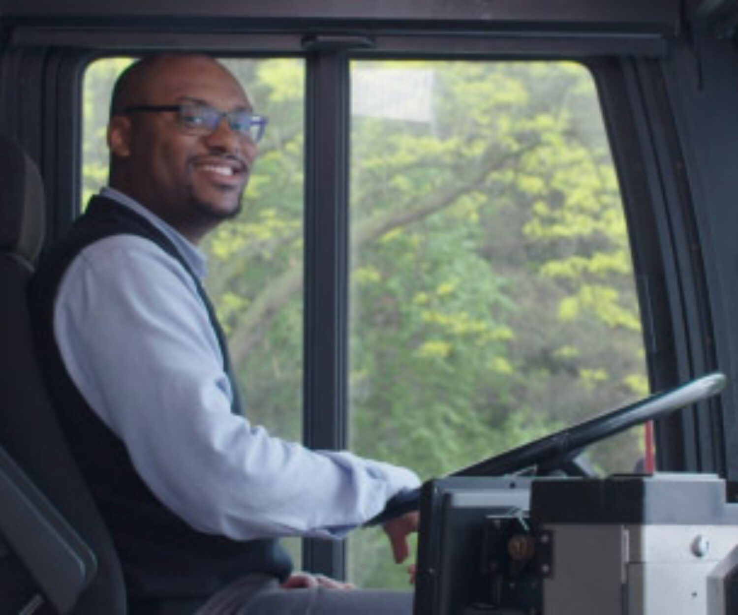 Man sitting in the driver seat of a bus on the set of "B" is for Bus Driver