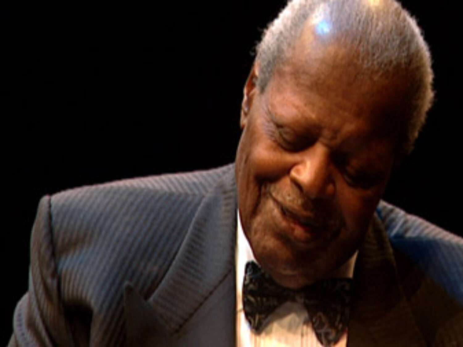 Oscar Peterson looking down at piano keys while playing