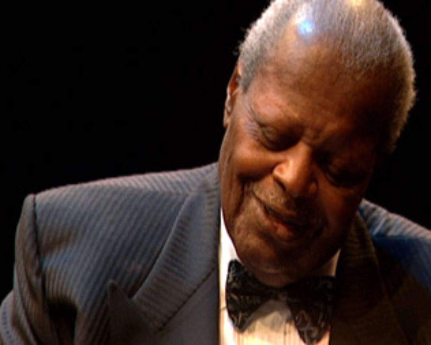 Oscar Peterson looking down at piano keys while playing